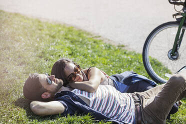 Romantic couple lying on grass at park - CAVF66772