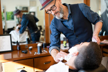 Friseur bereitet sich darauf vor, den Bart eines Kunden im Friseursalon zu rasieren - CUF52904