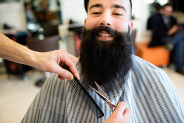 Friseur, der den Bart eines Kunden im Friseursalon trimmt - CUF52906
