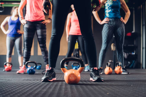 Frauen beim Training im Fitnessstudio, stehend an Kesselhanteln, ebenerdig - CUF52913