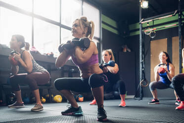 Frauen trainieren im Fitnessstudio, hocken mit Kettle Bells - CUF52914