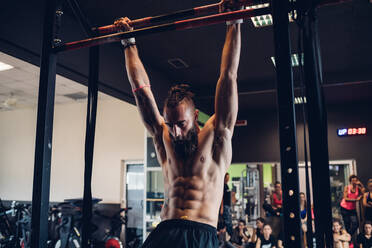 Junger Mann trainiert im Fitnessstudio, schwingt an der Stange - CUF52920