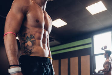 Junger tätowierter Mann beim Training im Fitnessstudio, Mittelteil Seitenansicht - CUF52923