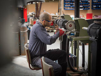 Knife factory worker using angle grinder in workshop - CUF52941