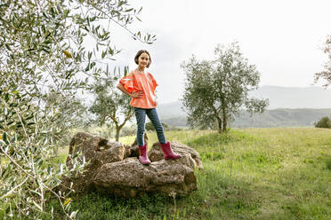 Niedliches Mädchen mit Bubikopf auf einem Felsen in malerischer Feldlandschaft stehend, Porträt, Citta della Pieve, Umbrien, Italien - CUF52975