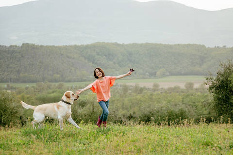 Mädchen läuft mit Labradorhund in malerischer Feldlandschaft, Citta della Pieve, Umbrien, Italien, lizenzfreies Stockfoto