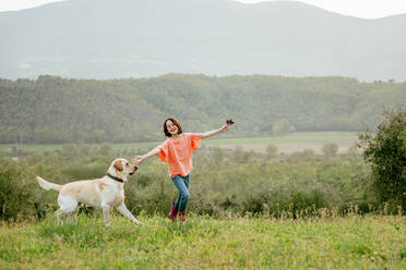 Mädchen läuft mit Labradorhund in malerischer Feldlandschaft, Citta della Pieve, Umbrien, Italien - CUF52981