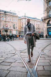 Stilvoller Mann geht über Straßenbahnschienen auf einer Piazza, Mailand, Italien - CUF53029