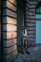 Stylish man using cellphone by period building, Milan, Italy - CUF53030