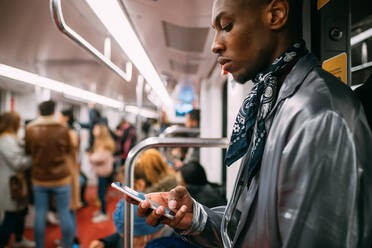 Stylish man using cellphone in train, Milan, Italy - CUF53033