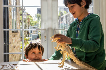 Junge und kleiner Bruder spielen mit Holzdinosaurier - CUF53070