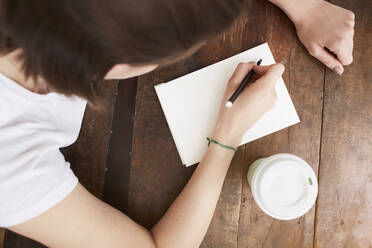 Woman writing on notebook at coffee break - CUF53081