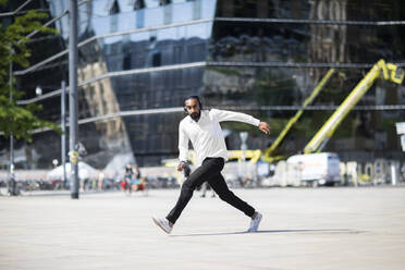 Man with headphones dancing in city - CUF53093