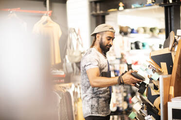 Man choosing skateboard in shop - CUF53100