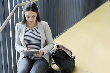 Geschäftsfrau benutzt digitales Tablet im Treppenhaus - CUF53117