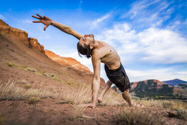 Mann ohne Hemd übt Yoga, während er gegen den Himmel im Bridger-Teton National Forest trainiert - CAVF66786