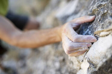 Ausgeschnittenes Bild eines Mannes, der auf einen Felsen klettert - CAVF66794