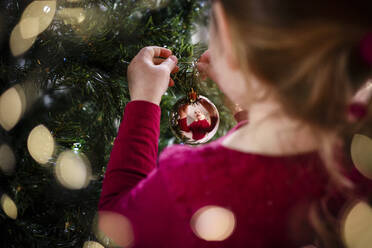 Festliches Bild von Mädchen schmücken Weihnachtsbaum Reflexion in Kugel - CAVF66842