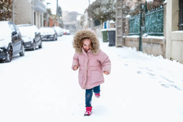 Young girl playing in street in snow in France facing camera - CAVF66843