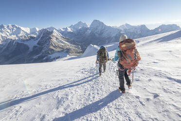 Bergsteigerin und kletternder Sirdar steigen einen Gletscher hinab, links der Everest - CAVF66878