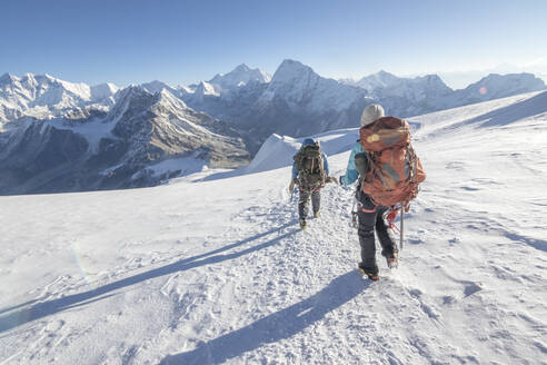 Woman mountaineer & cimbing Sirdar descend a glacier, Everest on left - CAVF66878