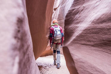 Canyoneer walks through a narrow section of a slot canyon - CAVF66880