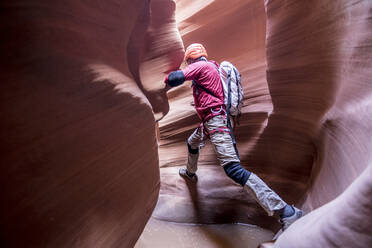 A canyoneer take a big step to avoid deep pothole in slot canyon - CAVF66882