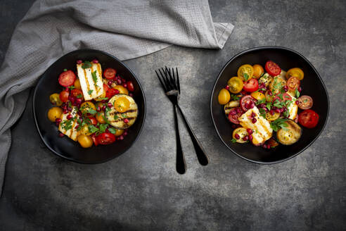 Schüsseln mit persischem Salat mit Tomaten, gegrilltem Halloumi-Käse, Auberginen, Granatapfelkernen, Sumach, schwarzem Sesam und Petersilie - LVF08411