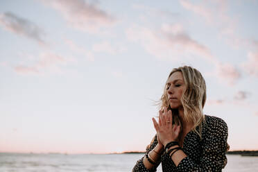 Junge Frau am Strand in Meditation bei Sonnenuntergang - CAVF66999