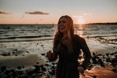 Woman laughing on the beach at sunset - CAVF67006