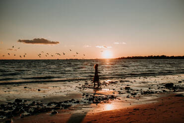 Frau geht am Strand mit Vögeln spazieren - CAVF67007