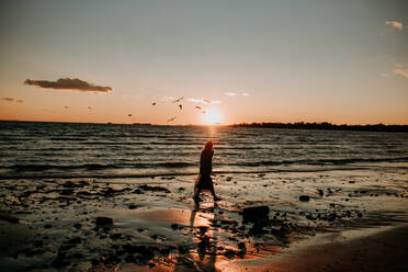 Frau geht bei Sonnenuntergang am Strand spazieren - CAVF67009