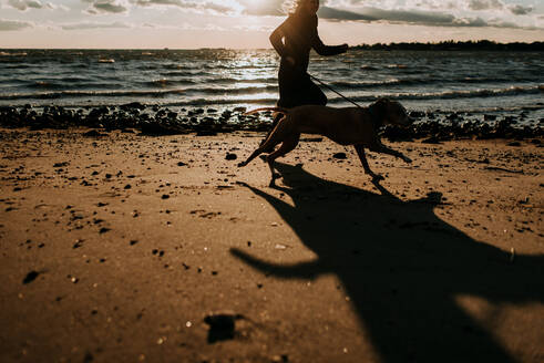 Frau läuft mit Hund am Strand - CAVF67035