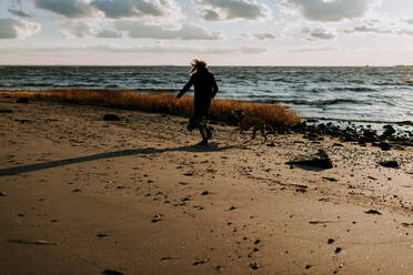 Woman running with dog on the beach - CAVF67036