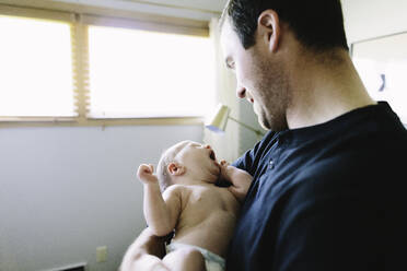 Ein frischgebackener Vater hält seinen neugeborenen Sohn, während er gähnt - CAVF67042