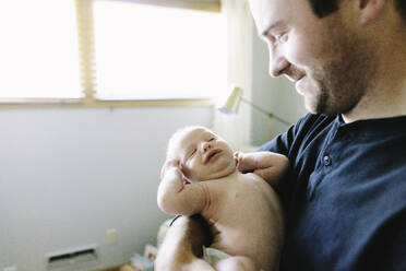 Ein frischgebackener Vater hält sein neugeborenes Baby, während er sich streckt - CAVF67045