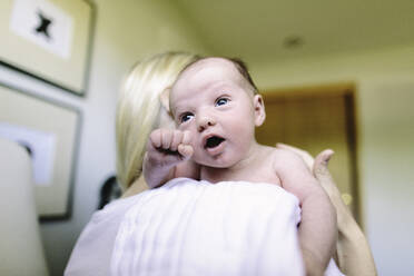 Over the shoulder view of a newborn baby boy in his mother's arms - CAVF67049