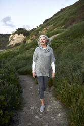 Ältere Frau in voller Länge auf dem Fußweg am Manhattan Beach bei Sonnenuntergang - CAVF67128