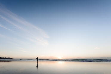 Silhouette person walking on peaceful beach at sunrise - CAVF67138