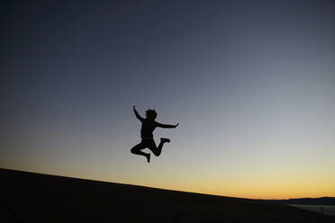 Silhouette woman jumping on land against clear sky during dusk - CAVF67165