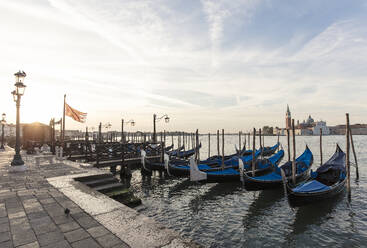 Gondolas moored on canal against Church of San Giorgio Maggiore and cloudy sky - CAVF67234