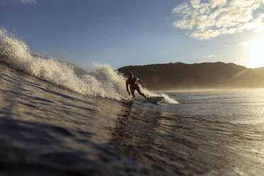 Surfer auf einer Welle bei Sonnenuntergang - CAVF67336