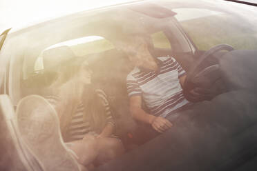 Ehepaar im Gespräch im Auto sitzend durch die Windschutzscheibe gesehen - CAVF67415
