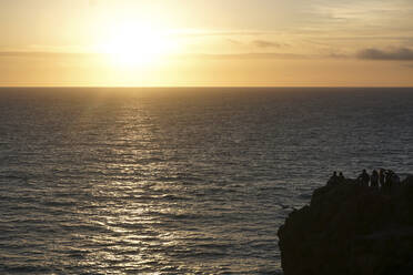 Silhouette people standing on cliff by sea against sky during sunset - CAVF67449