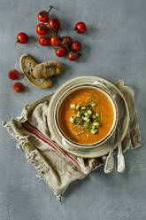 Overhead view of Gazpacho served in bowl by bread and cherry tomatoes at table - CAVF67472