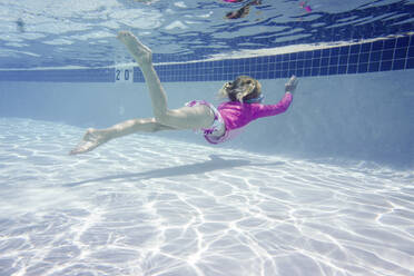 Mädchen schwimmt in voller Länge unter Wasser im Pool - CAVF67553