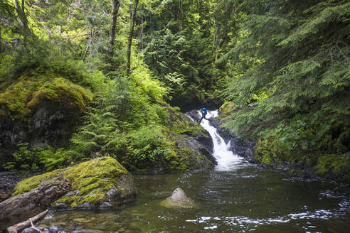 Rucksacktourist springt über einen Wasserfall in einer abgelegenen Gegend. - CAVF67605