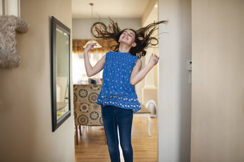 Teenager-Mädchen springt und dreht ihr Haar vor dem Spiegel zu Hause - CAVF67629