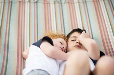 Brothers laying together with somber look in hammock - CAVF67632