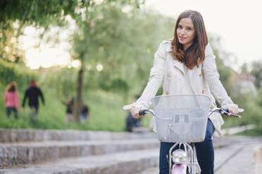 Portrait of woman with bicycle at park - CAVF67660